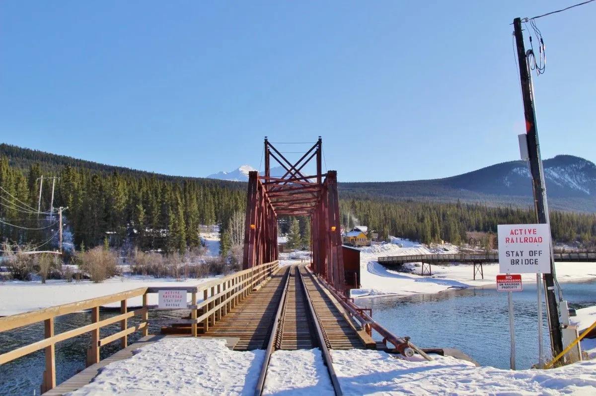 Voie ferrée qui traverse un pont métallique rouge au-dessus de la rivière, à Carcross en hiver