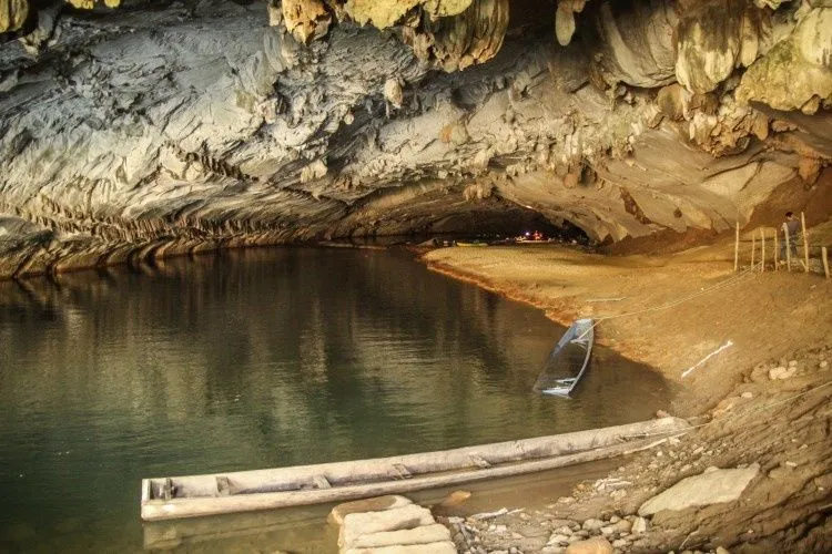 Rivière souterraine sous la voûte de la grotte de Kong Lo, avec des barques au bord